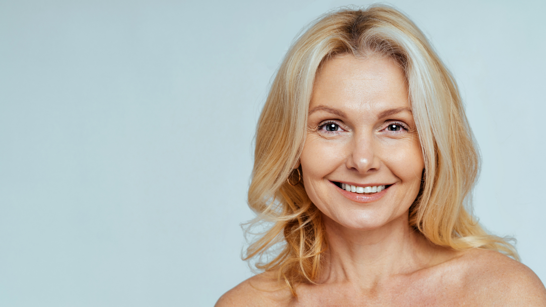 femme d'une quarantaine d'année blonde qui sourit sur un fond bleu